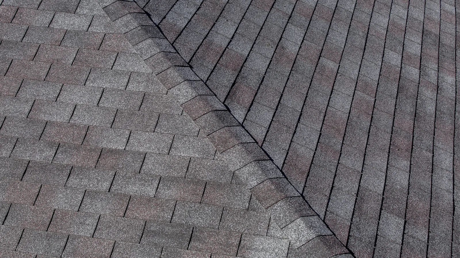 A hip ridge line running across gray three-tab asphalt shingle slopes