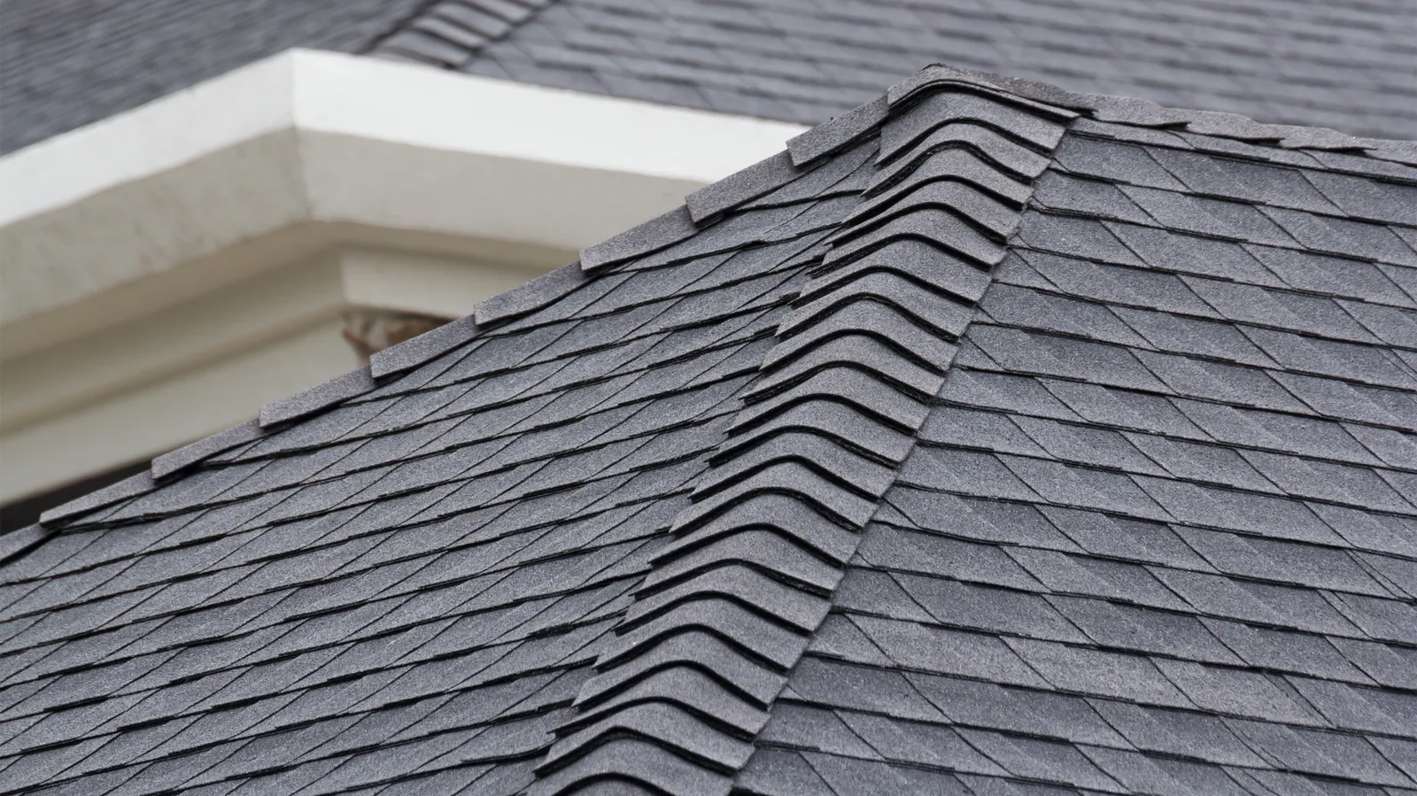 Along a gray shingle roof hip run ridge cap shingles