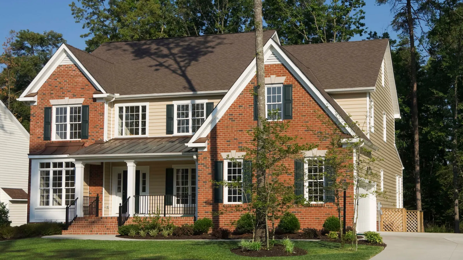 Two-story of red brick and siding under a brown asphalt shingle roof