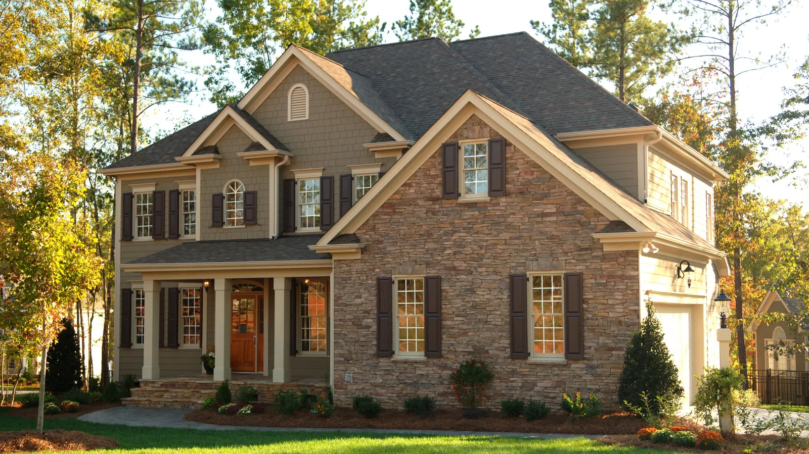 Two-story stone and siding home under a brown shingle roof