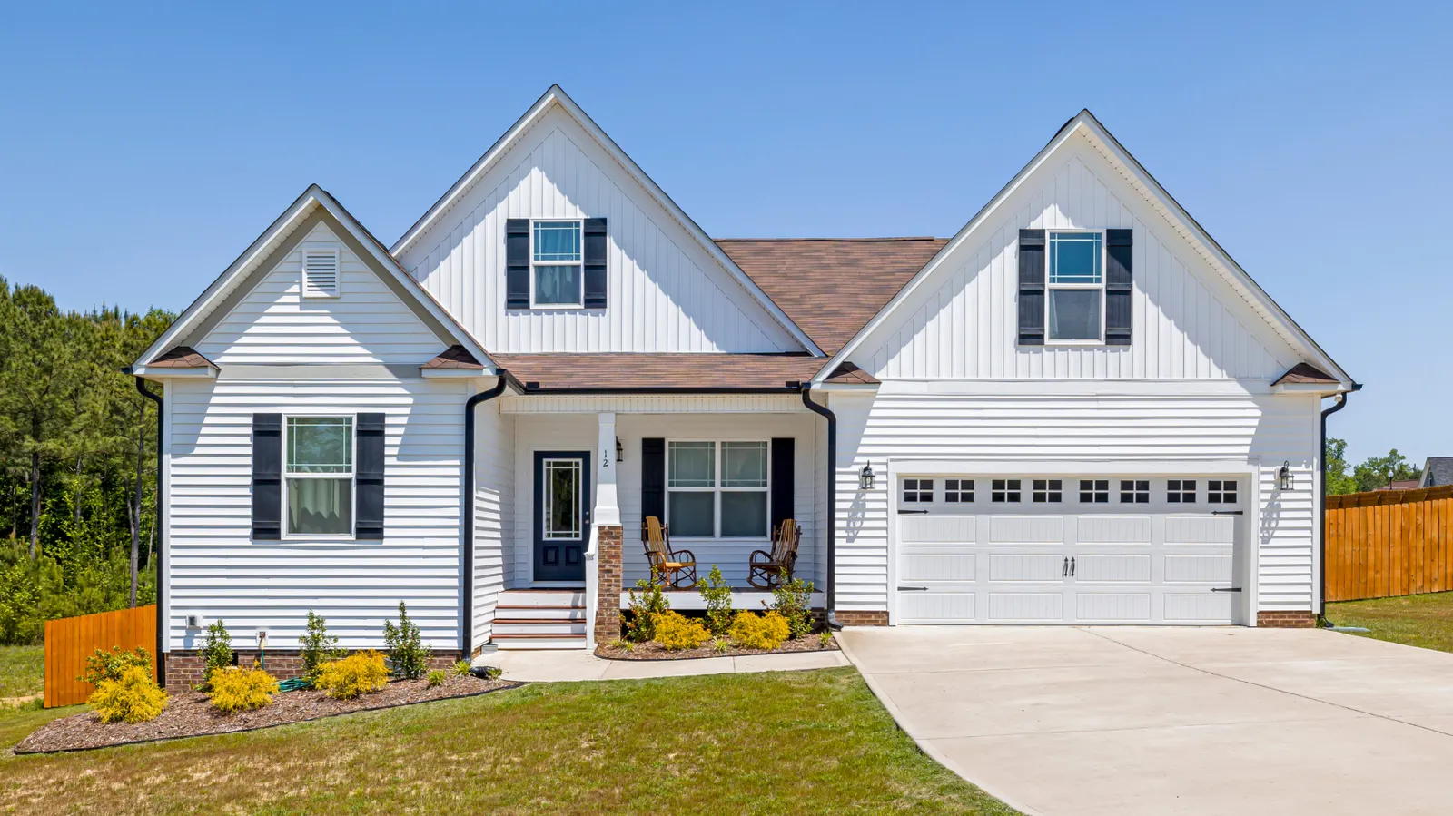 White home with brown shingle roof and attached two-car garage