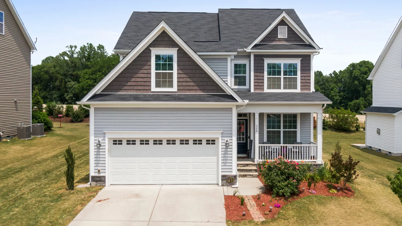 Covered front porch on a two-story home under a dark shingle roof