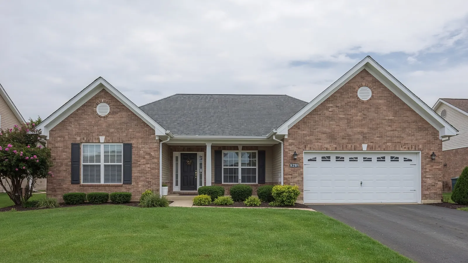 White garage door on a brick ranch home with a gray asphalt shingle roof