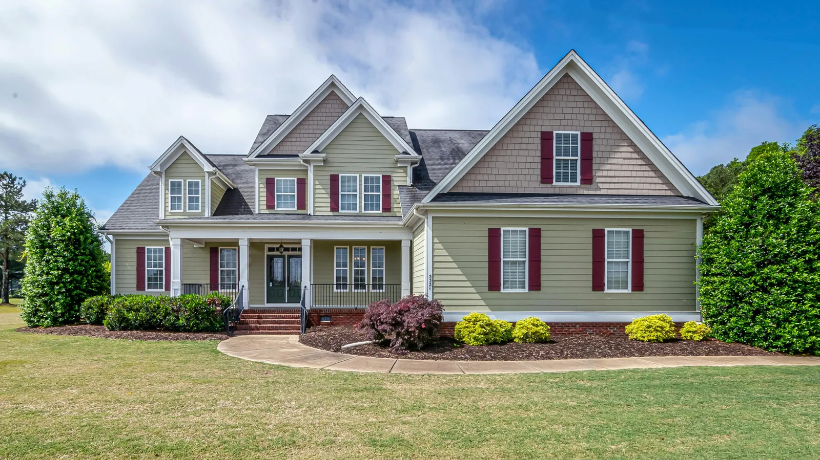 Dark shingle roof and red shutters on a sage green home