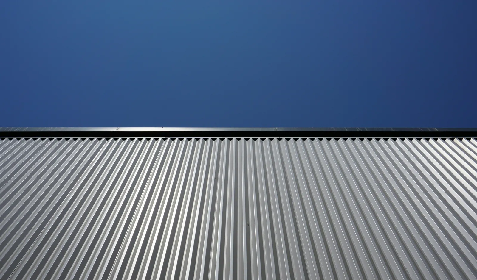 Corrugated silver metal panels set against a deep blue sky